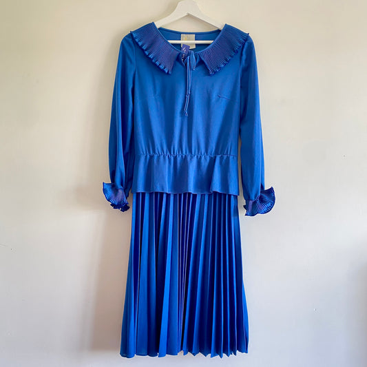 Late 70s vintage blue midi dress Pleat collar with tie Peplum to elasticated waist Pleated skirt Elasticated ruffle pleat cuff to sleeves Darts to bust Side zip 100% Polyester Machine washable 